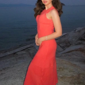 Rihoas Korallröd långklänning - Superfin korallröd långklänning från Rihoas med ärmlös design och snygg knytning i ryggen. Klänningen har en figurnära passform och är tillverkad i ett stickat material med diskret hålmönster nedtill. Perfekt för sommarkvällar och när du vill sticka ut.