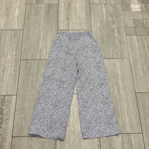 Lila leopardmönstrade byxor H&M - Säljer ett par lila byxor från H&M med svart leopardmönster. Byxorna har bred resår i midjan och är tillverkade i 100% polyester. Modellen är loose fit med raka, vida ben och känns riktigt sköna och lätta.