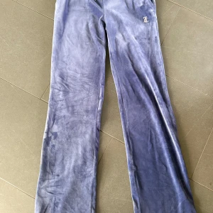 Lila velourbyxor från Juicy Couture - Mysiga lila mjukisbyxor från Juicy Couture i glansig velour med strassdetaljer och Juicy-logga på baksidan. Säljer de då dem aldrig har kommit till andvändning.storlek xs. Pris kan diskuteras vid snabb affär!