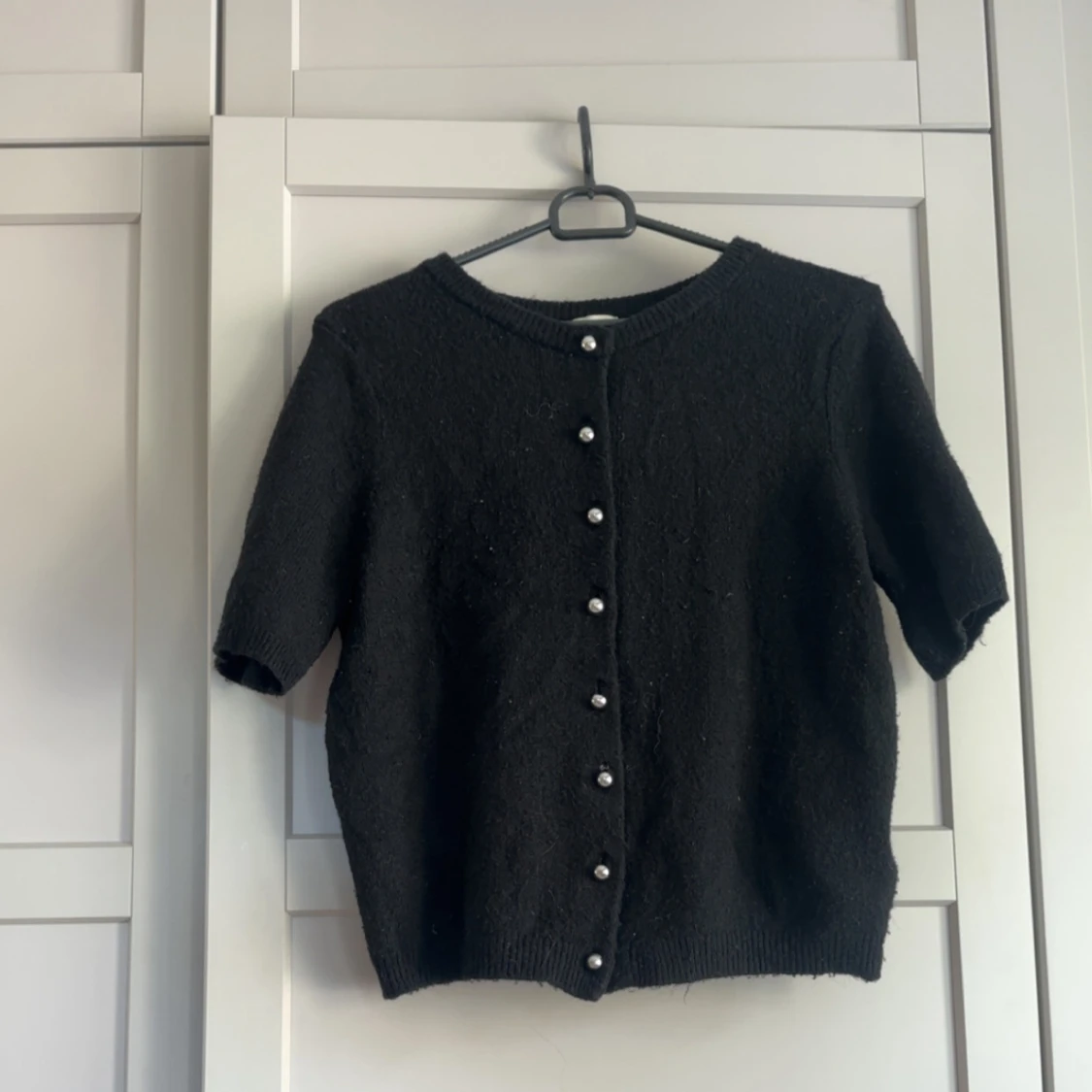 Svart kofta med pärlknappar