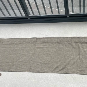 Brun linneliknande gardinkappa  - En stilren och lång gardinkappa med diskret vävd struktur. Tunt och luftigt tyg som ger en avslappnad vibe. Rektangulär form och enkel design gör den lätt att matcha. Bredd: 242cm Längd: 52,5cm 