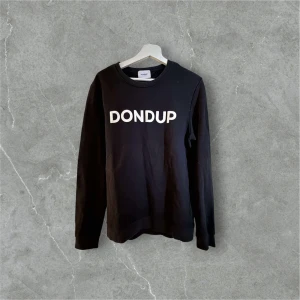 Dondup tröja - Svart sweatshirt från Dondup med vit logotyp framtill. Tröjan har rund halsringning och långa ärmar. Tillverkad i mjuk bomull för en skön känsla. Perfekt för en avslappnad och stilren look.