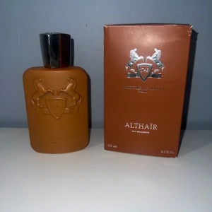 Parfums de Marly Althaïr 125ml - Exklusiv parfym, Althaïr från Parfums de Marly, 125 ml Eau de Parfum. Flaskan är matt brun med silverfärgad kork och har ett elegant reliefmönster med två hästar och sköld. Kommer i matchande brun kartong med silverdetaljer. Perfekt för dig som gillar lyxiga dofter.