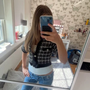 Svartvit rutig croppad kofta - Säljer en croppad kofta i svart och vitt med rutigt mönster och silvriga knappar. Koftan har korta ärmar, ribbade muddar och en snygg v-ringning. Perfekt att styla med jeans!💕Den är från hm och är i storlek S💕