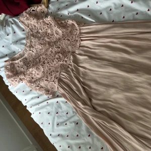 Ljusrosa långklänning - Superfin ljus rosa långklänning med överdel i vacker spets och underdel i mjukt, flowy tyg. Klänningen har ärmlös design och rund halsringning, perfekt för sommarens speciella tillfällen. Spetsen ger en romantisk vibe och kjolen faller snyggt.