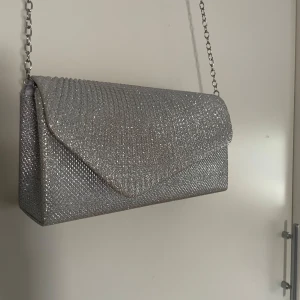 Glittrig silver väska  - Jag säljer denna super fina glittriga väska! Bandet går antigen att ha på eller ta av ifall att du vill hålla väskan i handen istället! 🫶🏼Endast använd en gång under min bal! 