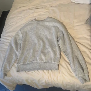 Grå basic sweatshirt - Enkel och stilren grå sweatshirt med rund hals och långa ärmar från Gina Tricot. Tröjan har ribbade muddar vid ärmslut och midja, perfekt för en avslappnad look. Passar till allt och är superbekväm tack vare mjukt material.