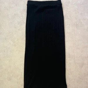 Svart långkjol från LMTD - Säljer en svart långkjol från LMTD i storlek XS. Kjolen har en rak passform, en liten slit som gör de 100x finare och är ribbad med diskreta vertikala ränder. Perfekt att styla med en crop top eller oversized hoodie för en chill look. Använt ENDAST en gång