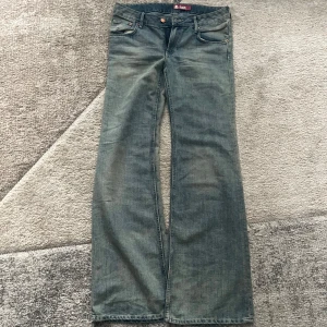 Blå bootcut jeans & Flary - Snygga blå bootcut jeans från & Flary med klassisk femficksdesign och lätt slitning. Jeansen har normal passform och är tillverkade i mjukt denimtyg som ger en skön känsla. Perfekta för dig som gillar retrovibbar och vill ha ett par jeans med lite extra sväng i benen.
