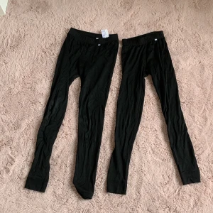 Svarta underställsbyxor Helly Hansen - Två par svarta underställsbyxor från Helly Hansen. De är tighta och gjorda i mjukt syntetmaterial som andas, perfekta för lager-på-lager under vintern. Resår i midjan och smal passform hela vägen ner.