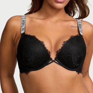 Victoria secret svart spetsig push-up bh - Svart push-up topp med spetsdetaljer och tunna korsade band framtill. Axelbanden har en cool logotyptext i vitt som ger en sportig touch. Perfekt för dig som gillar en mix av sportigt och feminint. FRÅGA OM DU VILL SE EGNA BILDER 🩷 säljer pga inte min storlek
