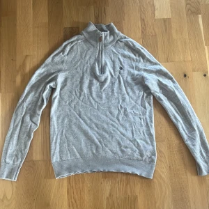 Beige half zip tröja med hög krage från Morris - Snygg Beige tröja från Morris med hög krage och half zip-dragkedja. Tröjan har lång ärm, ribbade muddar och en liten broderad logga på bröstet. Perfekt för lager-på-lager och chill stil. Storlek M men sitter som XS 