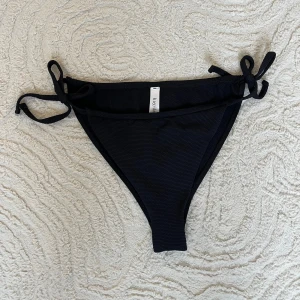 Svarta bikinitrosor från Kay/Day (Kappahl) - Enkla svarta bikinitrosor från Kay/Day i storlek S. Bikiniunderdelen har knytband i sidorna vilket gör att de är justerbara. Den är väldigt enkel att matcha med olika överdelar.