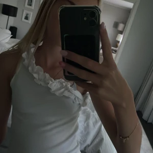Vit one shoulder topp med volang från Kappahl  - Supersöt vit ribbad topp med one shoulder och bred volang längs halsringningen. Sitter tight och har en fräsch, somrig vibe. Perfekt för dig som vill sticka ut med en unik detalj på axeln. Från Kappahl🤍🤍
