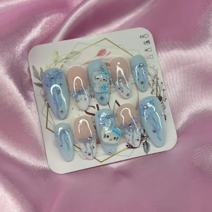 SkyKitty (S);Medium Almond - Snygga gelé press-on naglar i medium mandelform med ljusblå och nude bas, dekorerade med handmålade rosetter, strasstenar och söta Hello Kitty-detaljer. Perfekt för dig som vill ha en unik och söt nageldesign med 3D-effekt och glansig finish. I storlek S: 15 mm, 11,5 mm, 12 mm, 11 mm, 9 mm 