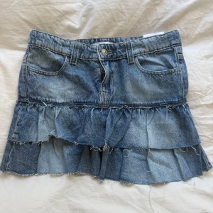 Jeans kjol med volanger  - Säljer denna slutsålda jeanskjol med volanger från gina young, storlek 158. Helt ny med prislapp och aldrig använd!
