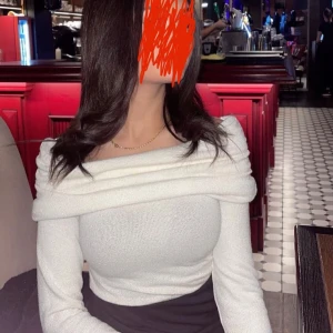 Vit offshoulder topp - Supersnygg vit offshoulder topp med glittrig finish och långa ärmar. Toppen har en bred, vikt krage som ger en elegant look och sitter tight över kroppen. Perfekt för dig som vill sticka ut med stilren och trendig vibe.