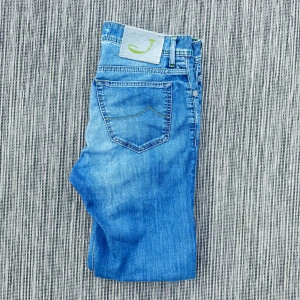Jacob Cohen  - Snygga blå jeans med en cool ljusgrön J-detalj på bakfickan. Klassisk femficksmodell i mjukt denimtyg, perfekt för dig som gillar en avslappnad och trendig look.!AI BESKRVINING! Om ni vill ha fler bilder eller om ni har andra funderingar och frågor skriv.