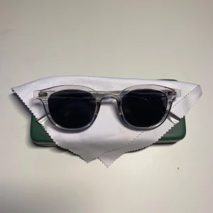 Solglasögon från Montén - Snygga solbrillor från Montén med transparent båge och runda, mörktonade glas. Ramen är i plast och ger en modern, clean look. Perfekta för dig som vill sticka ut med stilrena accessoarer. Kommer med grön fodral och putsduk.