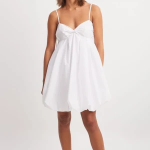 Vit kort klänning med rosettband - Supersöt vit kortklänning med tunna axelband som knyts med rosett på axlarna. Slutsåld på hemsidan!💓💓🙌använd fåtal gånger 