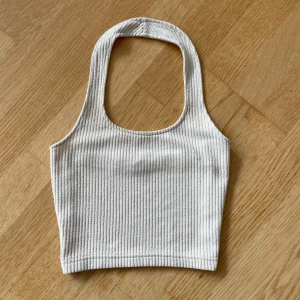 Crémefärgad croppad halterneck  - ribbad ljust beige linnetopp från H&M Divided i storlek XS.  Enkel och stilren design som passar till allt. Kolla gärna in mina andra annonser också😚💗