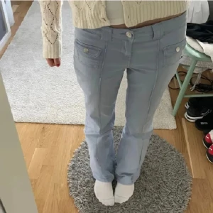 Lågmidjade jeans - Ett par såå snygga ljusblå byxor med bootcut och snygga fickor framtill med knappar. Byxorna har låg midja och är perfekta för dig som gillar en avslappnad men trendig stil. Aldrig kommit till användning så som nya!💕