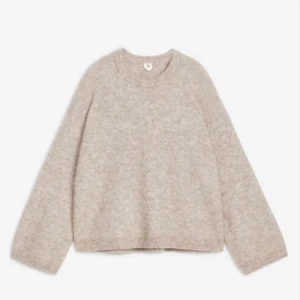 Beige stickad tröja från Arket - Supermjuk beige stickad tröja från Arket i en loose passform. Tröjan har rund halsringning, långa ärmar och ribbade muddar. Perfekt för lager-på-lager och chill höst- och vinterstil.