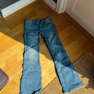 Blå bootcut jeans från Gina Tricot - Snygga blå jeans från Gina Tricot i bootcut-modell. Klassisk femficksdesign, normal passform och tillverkade i mjukt denimtyg. Perfekta för dig som gillar en avslappnad men trendig look.