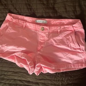 Rosa shorts från Abercrombie & Fitch - Snygga rosa shorts från Abercrombie & Fitch med klassisk passform. De har fickor fram och bak, bälteshällor och stängs med knapp och dragkedja. Perfekta för sommardagar och lätta att matcha med en enkel t-shirt eller linne!Midjemåttet tvärs över är 42.💕💕
