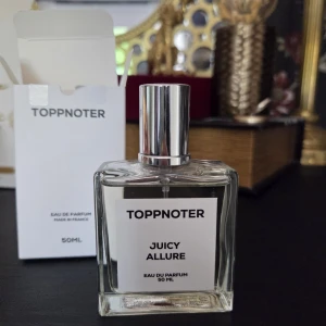 Toppnoter Juicy Allure Eau de Parfum - Juicy Allure från Toppnoter är en Eau de Parfum på 50 ml i en stilren, fyrkantig glasflaska med silverfärgad kork. Doften har friska noter av saftiga bär, jasmin, mandelblom, vanilj och söt kolasås. Perfekt för dig som gillar fruktiga och blommiga parfymer med en varm, söt bas.