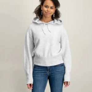 Ljusgrå stickad hoodie med huva - Mysig ljusgrå stickad hoodie med huva och snörning. Tröjan har lång ärm, ribbade muddar och avslappnad passform. Perfekt för lager-på-lager och chill dagar.