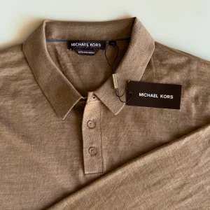 Beige pikétröja från Michael Kors - Ny och oanvänd beige långärmad pikétröja från Michael Kors i mjuk och 100% tunn merinoull. Nypris 1350kr.