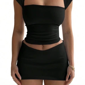 Svart croppad topp - Säljer en svart croppad topp med tight passform och korta ärmar och även en svart kort kjol till . Toppen har en fyrkantig urringning och är tillverkad i ett stretchigt material som sitter snyggt på kroppen. Perfekt att matcha med kjol eller jeans.