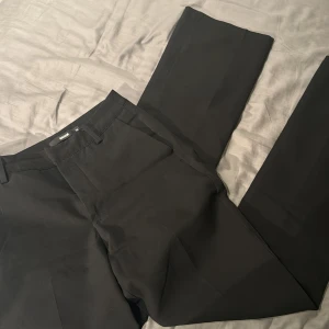 Svarta kostymbyxor från BikBok - Snygga svarta kostymbyxor från BikBok med klassisk passform. Perfekta för en stilren look och enkla att matcha med olika toppar. Gjorda i ett mjukt och bekvämt material.