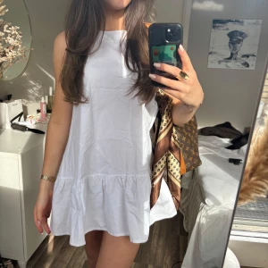 Vit ärmlös volangklänning - Passar super fint till studenten🥰 Säljer en söt vit ärmlös klänning med volang nertill. Klänningen har en luftig och avslappnad passform, perfekt för varma dagar. Enkel och stilren design som är lätt att matcha med accessoarer.