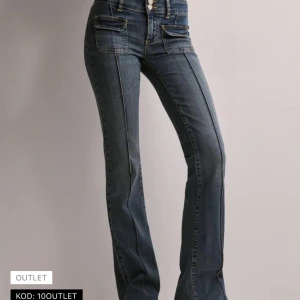 Blå bootcut jeans med fickdetaljer - Snygga blå bootcut jeans med markerade sömmar och stora fickor framtill. Jeansen har hög midja och klassiska bakfickor. Perfekta för dig som gillar en retroinspirerad look med lite utsvängda ben. Jättefint skick, knappt använda. 