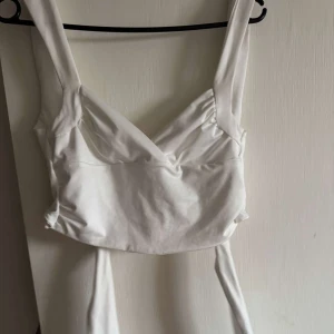Vit croppad linnetopp - Säljer en vit croppad linnetopp med breda axelband, ur ringad rygg och man knyter banden långt ner på ryggen💕
