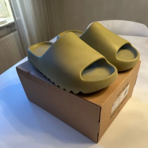 Adidas Yeezy Slide (resin) - Säljer ett par Adidas Yeezy Slide (resin).  Aldrig använda utan bara testade en gång! Säljer för att de bara legat i kartongen och aldrig använt dem.  Kommer med originalkartong och alla tags.          Skick- 10/10                                                                     Storlek- 44,5