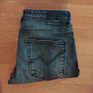 Grå tom Tailor jeans  - Säljer ett par grå slim fit jeans med klassisk femficksdesign och dragkedja. Jeansen har en något tvättad look och smal passform hela vägen ner. Perfekta till vardags för en stilren och enkel outfit.(ny pris 899) (mitt pris 399)