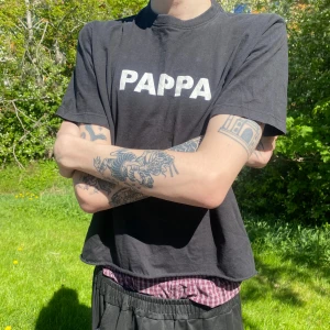 PAPPA t-shirt - Svart t-shirt med vit text 'PAPPA' på bröstet. Klippt nedtill. En toppentisha! Kanske till farsdag? Pojkvännen? Nyblivna pappan? Passar egentligen till vilken person o byxa som helst! :-P