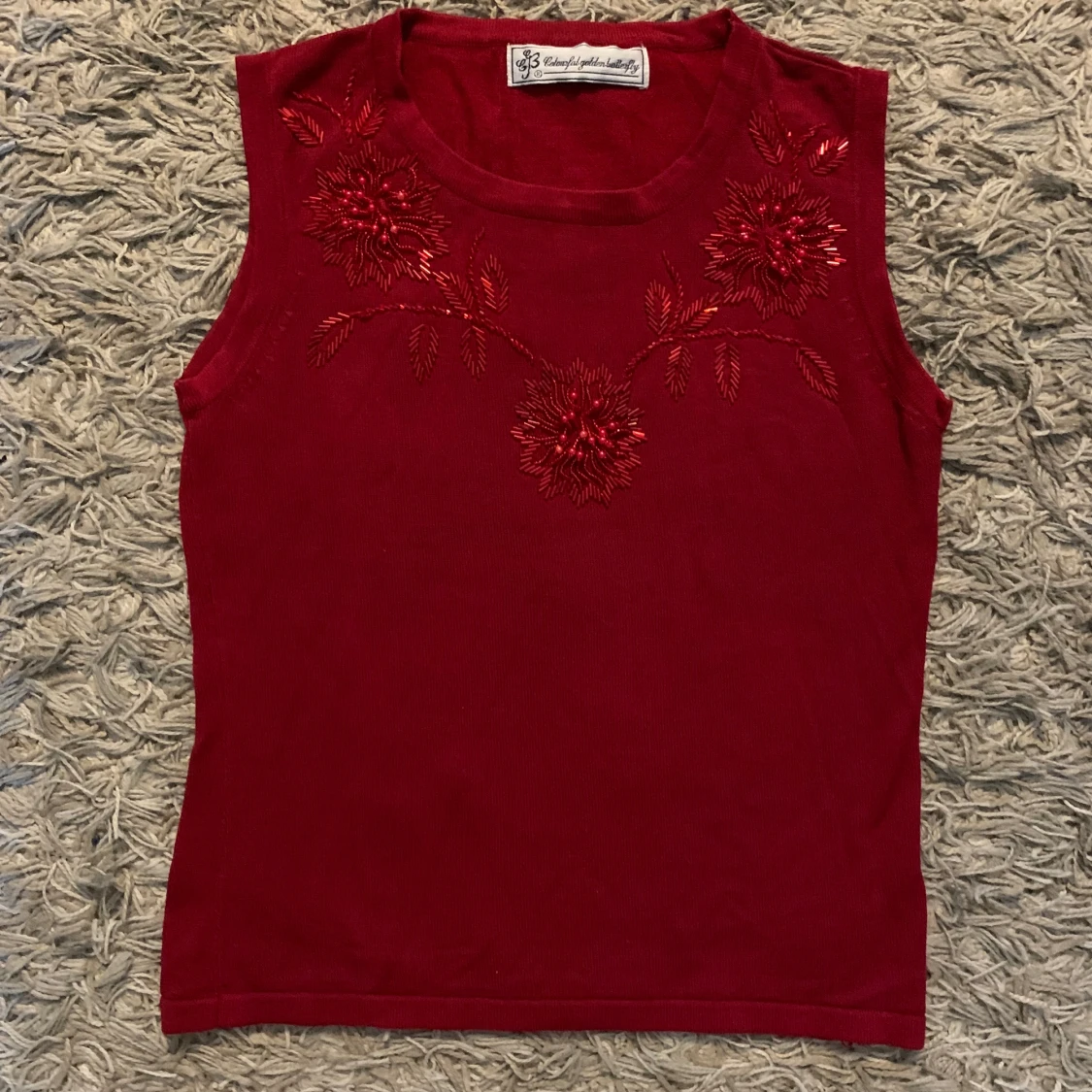 Röd ärmlös topp med broderade blommor