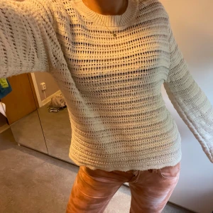 Vit stickad tröja med hålmönster - Strl står att den är i L men den sitter som en S (jag har S på bilden) Säljer en vit stickad tröja med hålmönster och rund hals. Tröjan har lång ärm som går ut lite och är mjuk och skön, Passformen är normal och modellen är klassisk. 