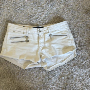 Beiga shorts med dragkedjor från Xoul Edition - Skit snygga shorts i vit med dragkedjor som dekoration på framsidan och är lågmidjade. De är från början ett par jeans jag klippt av och skulle säga att de passar s-m