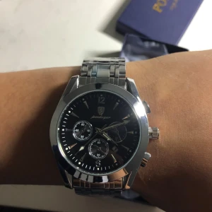 Silverfärgad klocka från Bewellager - Stilren herrklocka i silver med svart urtavla och tre mindre subdials. Klockan har en robust länkarmband i metall och tydliga indexmarkeringar. Perfekt accessoar för dig som gillar klassisk design.