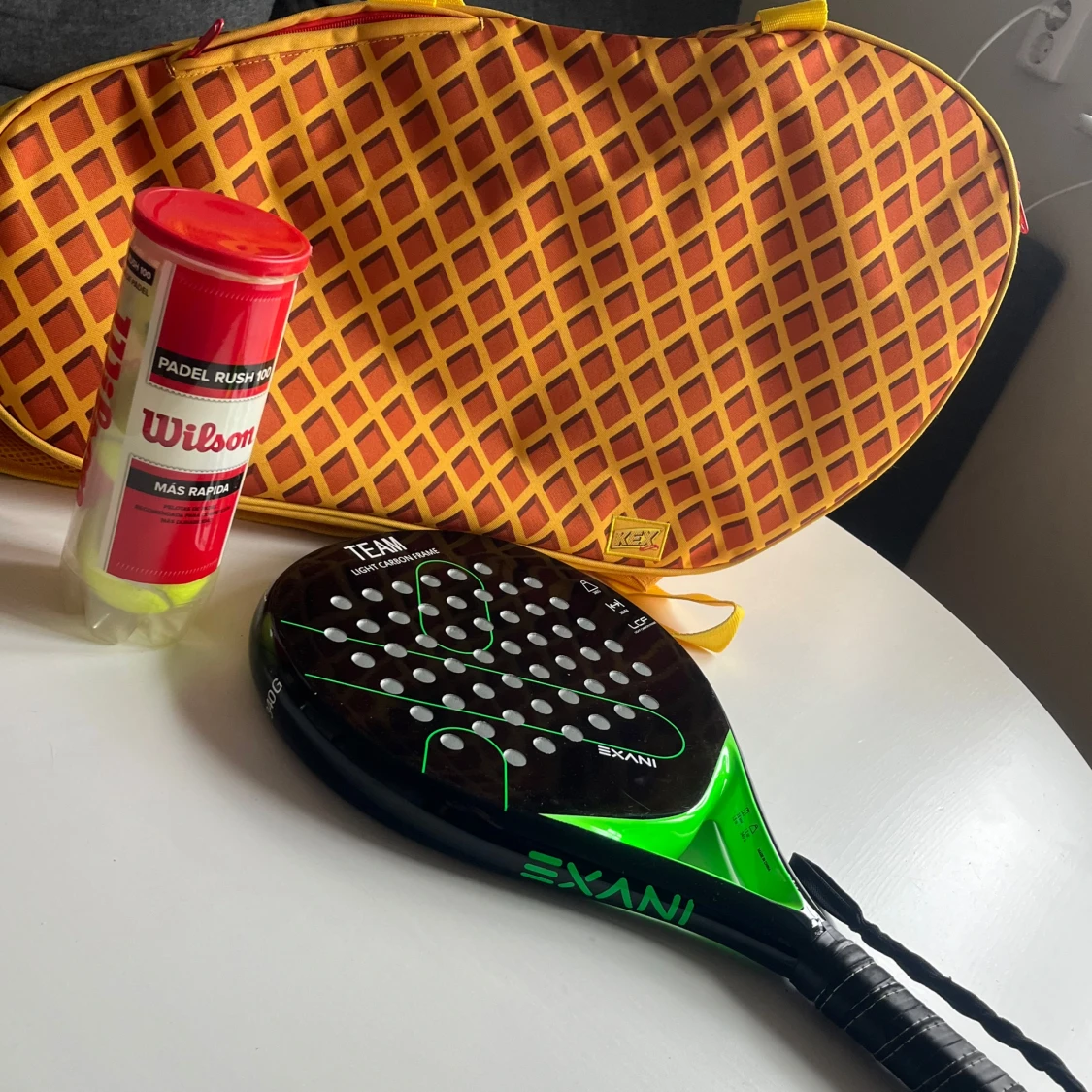 Gul- och orange padelväska från kexchoklad med paddelrack och bollar till