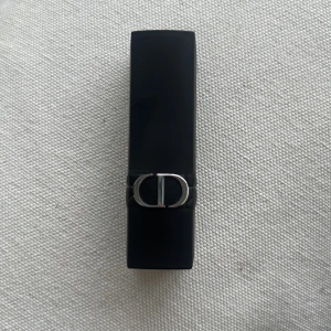 Dior Addict läppstift 506 - Säljer ett Dior Addict läppstift i nyansen 506. Hylsan är svart med silverdetaljer och CD-logga. Färgen är en mjuk, neutral rosa-nude ton som passar perfekt till vardags. Lyxig och elegant design med klassisk Dior-känsla. Kommer utan förpackning, oanvänd och otestad, om du köper fler av dessa läppstift kan jag tänka mig bättre pris. Rensning inför flytt. Vissa märken på själva skalet på läppstiftet kan förekomma då jag förvarat alla i samma låda 