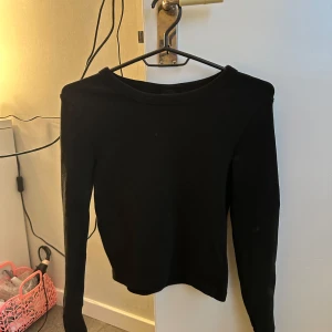 Svart croppad långärmad tröja - En enkel svart croppad tröja med långa ärmar och rund halsringning. Perfekt att styla med jeans eller kjol för en clean look. Mjuk och skön, passar till många olika outfits.