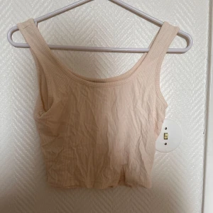 Beige ribbad croppad linnetopp från SHEIN - Säljer en beige croppad linnetopp från SHEIN i ribbat material. Toppen har breda axelband och rundad halsringning, perfekt för varma dagar eller som lager under skjorta.