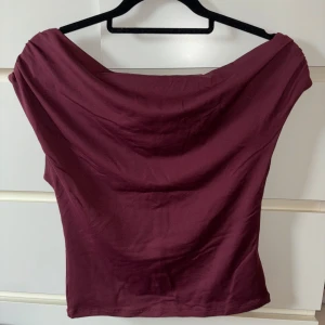 Burgundy festtopp - Säljer en nästan oanvänd festtopp (använd en gång) från Gina Tricot. Storlek M, något croppad. Den är asymmetrisk i ”kragen” och man kan ha den på olika sätt🥰 Säljer då den inte används.