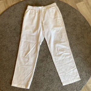 Vita linnebyxor  - Säljer ett par vita linnebyxor med resår i midjan och raka ben. Perfekta för varma dagar och har en avslappnad passform. Byxorna har fickor i sidorna och är lätta och luftiga. Märke på byxorna finns inte då lappen är bortklippt, därav nedsatt pris.
